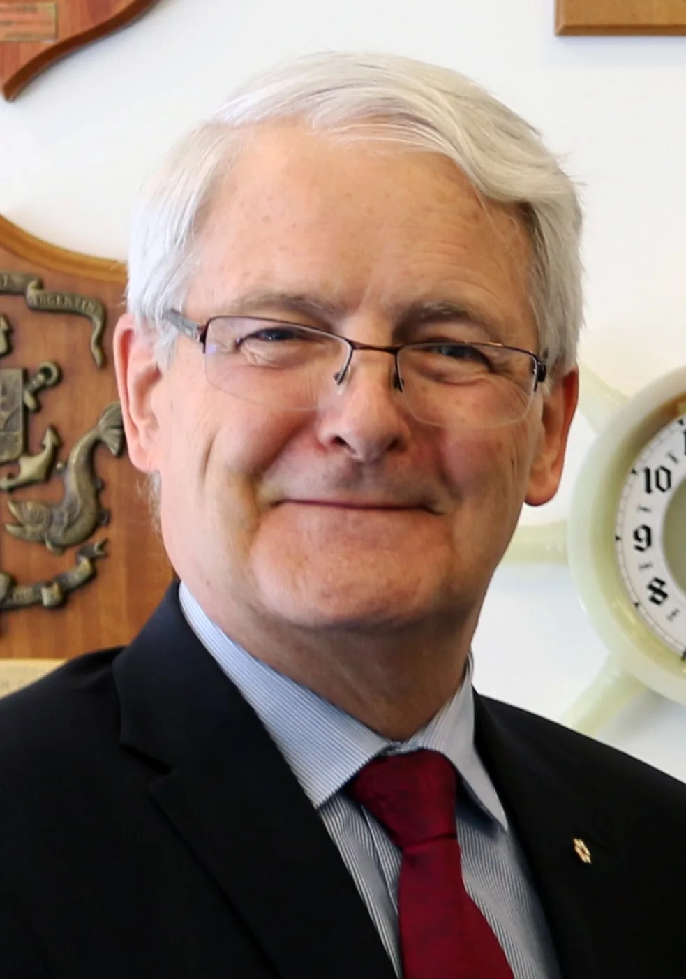 Marc Garneau with gray hair and glasses wearing a dark suit and red tie in a later portrait