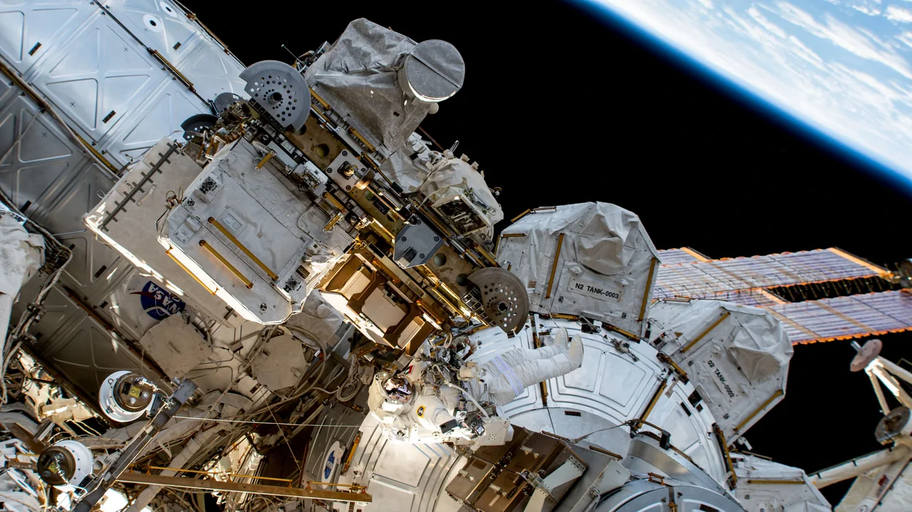 Sultan Alneyadi in a white spacesuit beside the International Space Station’s Quest airlock, with station hardware and Earth’s curved horizon beyond