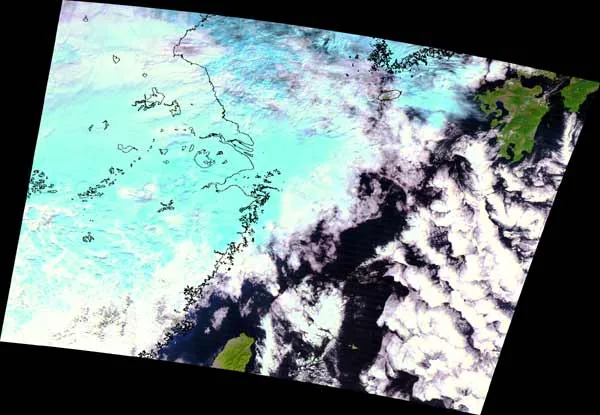 Tilted processed satellite scene of Kyushu and the East China Sea, with white and blue cloud systems, green land and black margins.