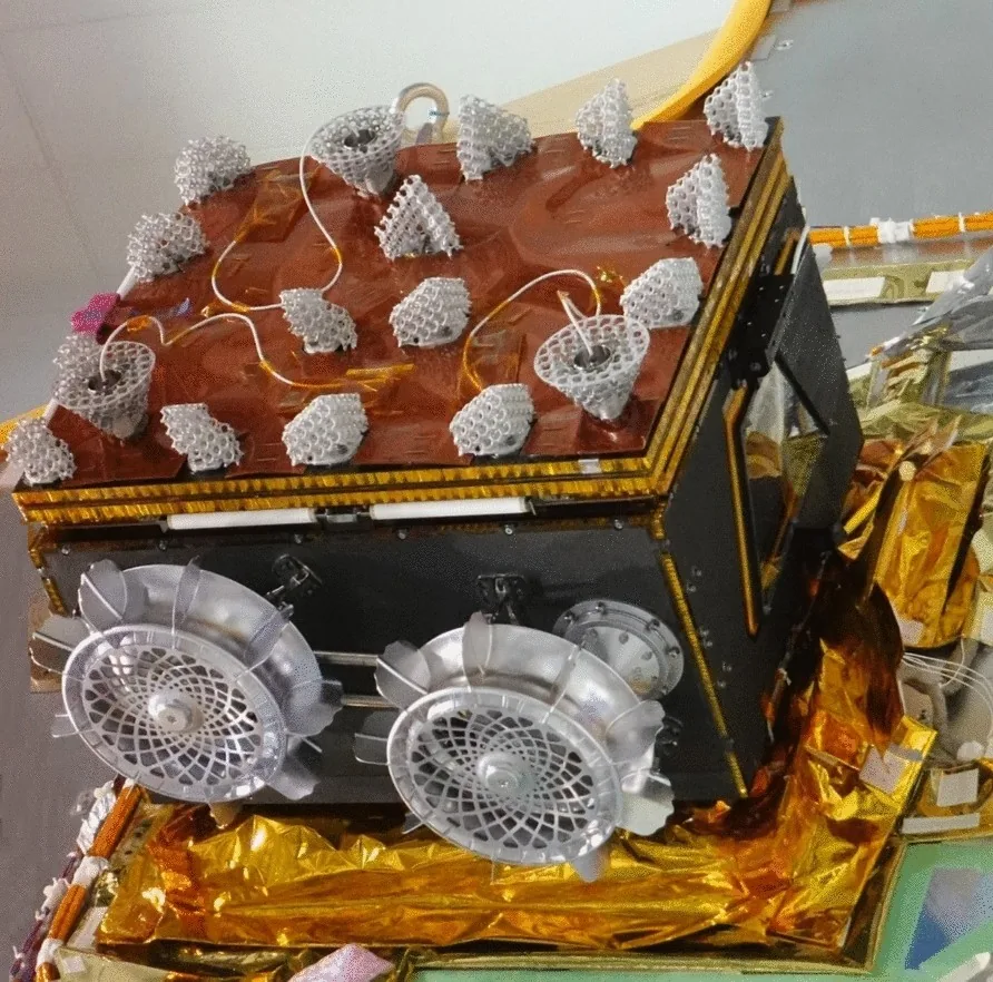 Idefix flight rover in a ground integration facility, with two silver wheels visible beside a dark box-shaped body, a covered top panel and gold-colored insulation below.