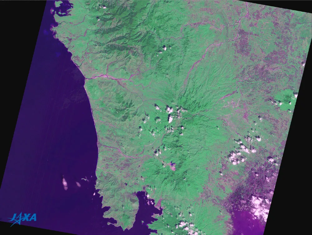 Processed satellite observation shows the Pinatubo region in green and purple, with the coast at left and small white clouds.