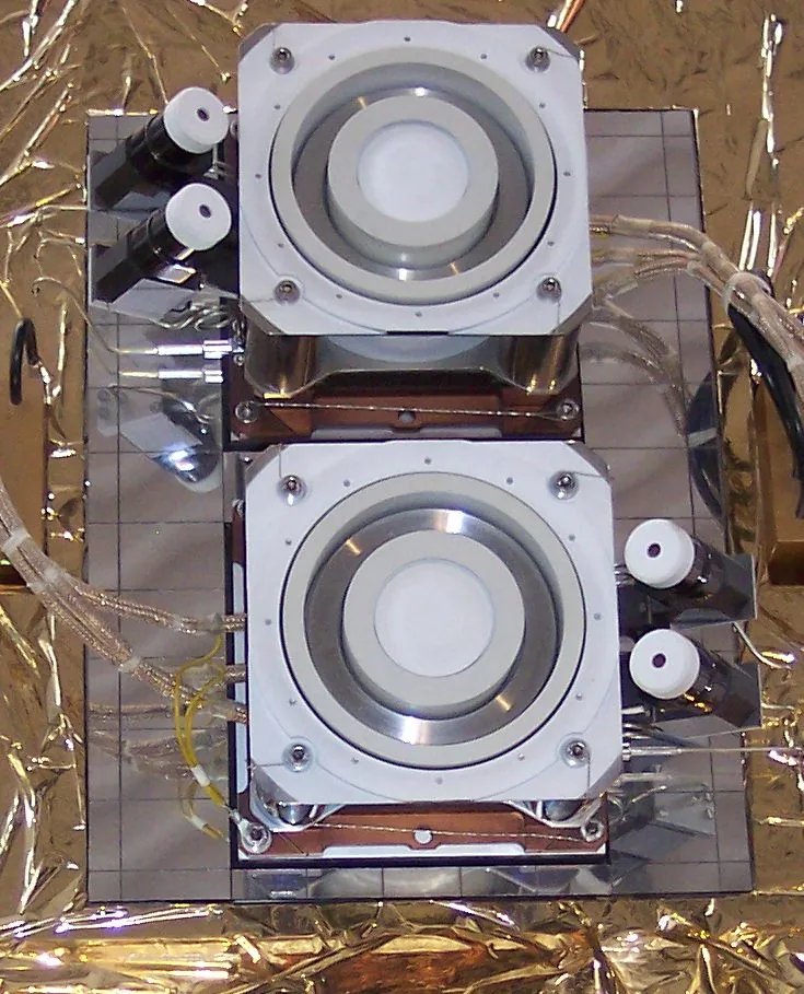 Two PPS-1350 Hall-thruster units with circular annular discharge channels and nearby fittings on reflective support hardware