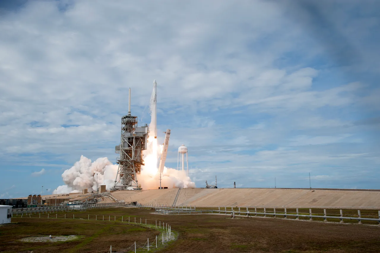 Falcon 9 lifts off beside its launch tower, carrying Dragon beneath a cloud-streaked sky