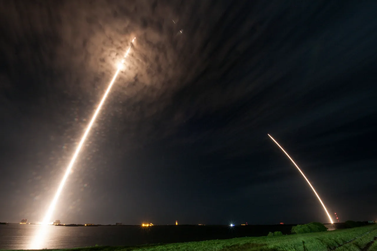 Two luminous trails in a long exposure record the CRS-9 launch at left and first-stage return at right above a coastal horizon