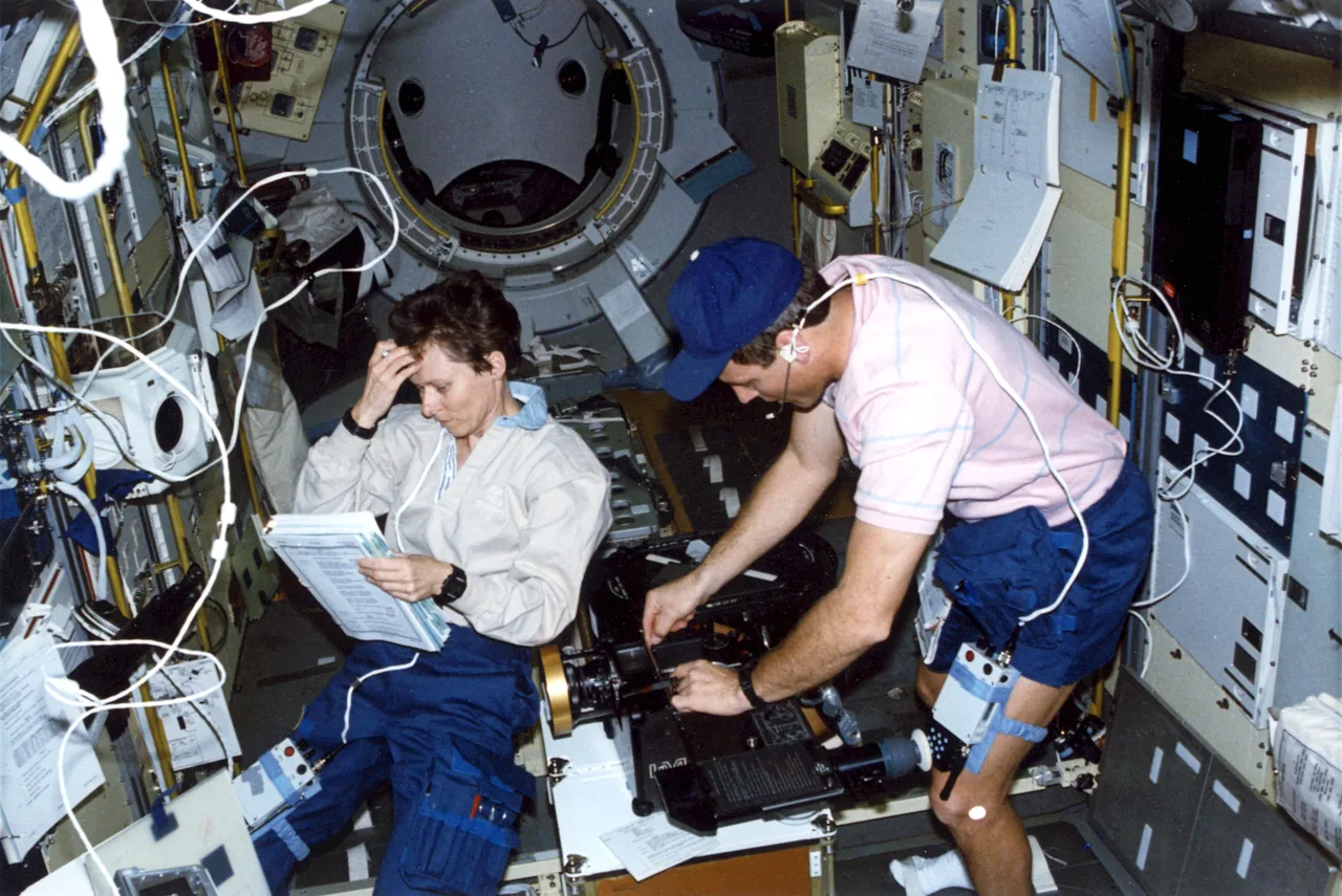 Roberta Bondar and Stephen Oswald work among equipment inside the IML-1 laboratory