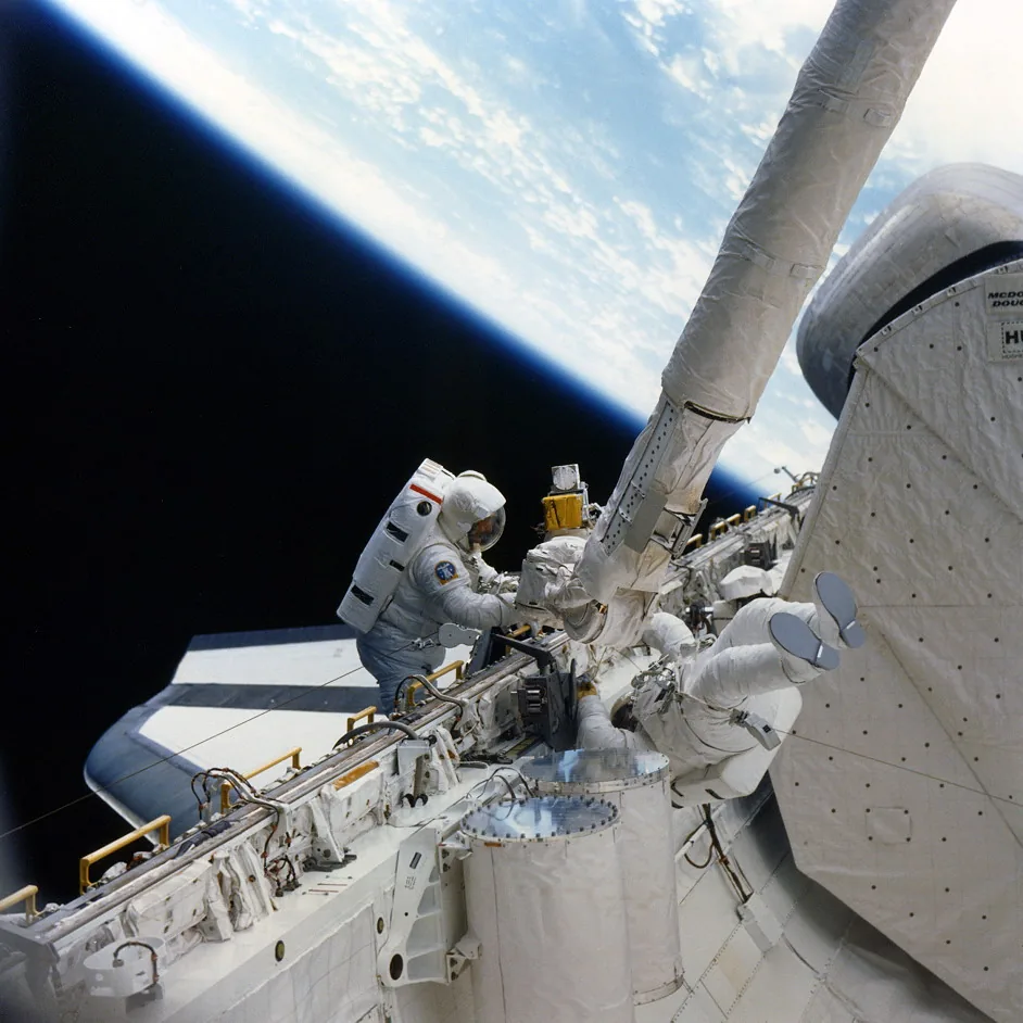 Jeffrey Hoffman and David Griggs attach an improvised flyswatter tool to Canadarm during STS-51-D