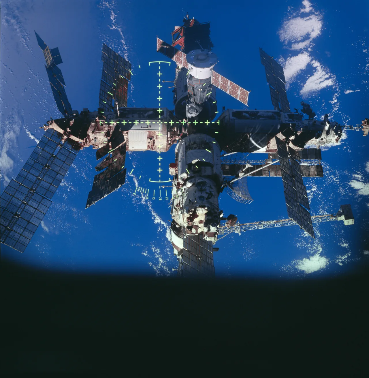 Mir’s modules and solar arrays appear above blue ocean with alignment-sight markings over the center