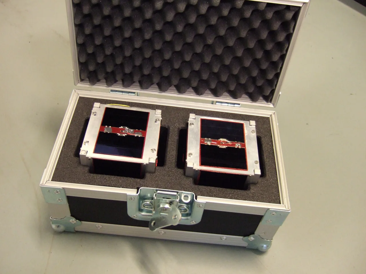 Two small AAUSAT-II assemblies sit in separate recesses of a foam-lined transport case