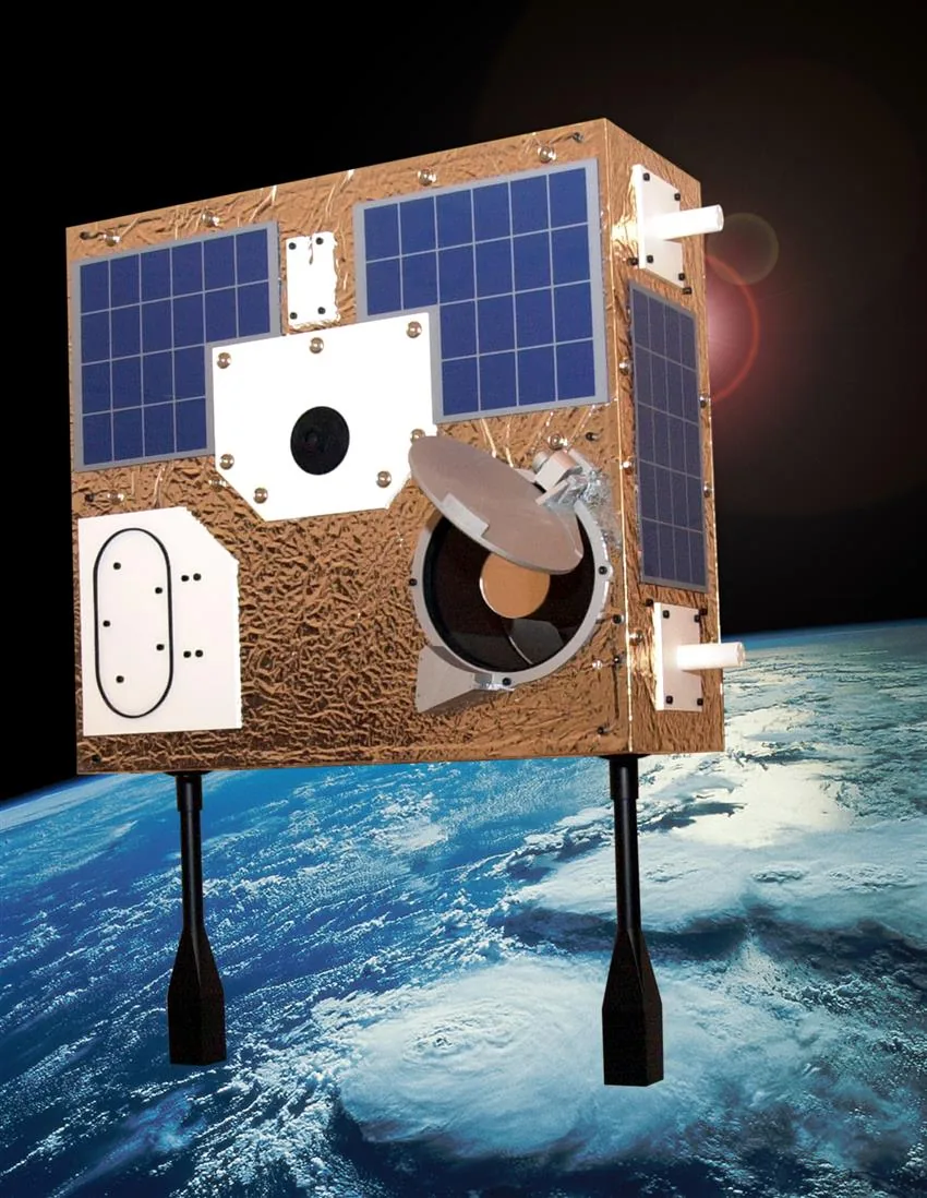 Gold-covered MOST model with blue solar panels, an open telescope cover and visible support posts against an Earth backdrop