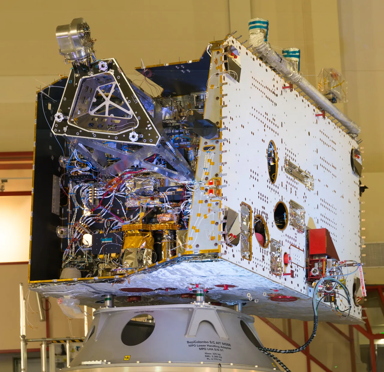 BepiColombo MPO stands on a support fixture, with a broad white panel and exposed wiring and insulated components inside its open side.