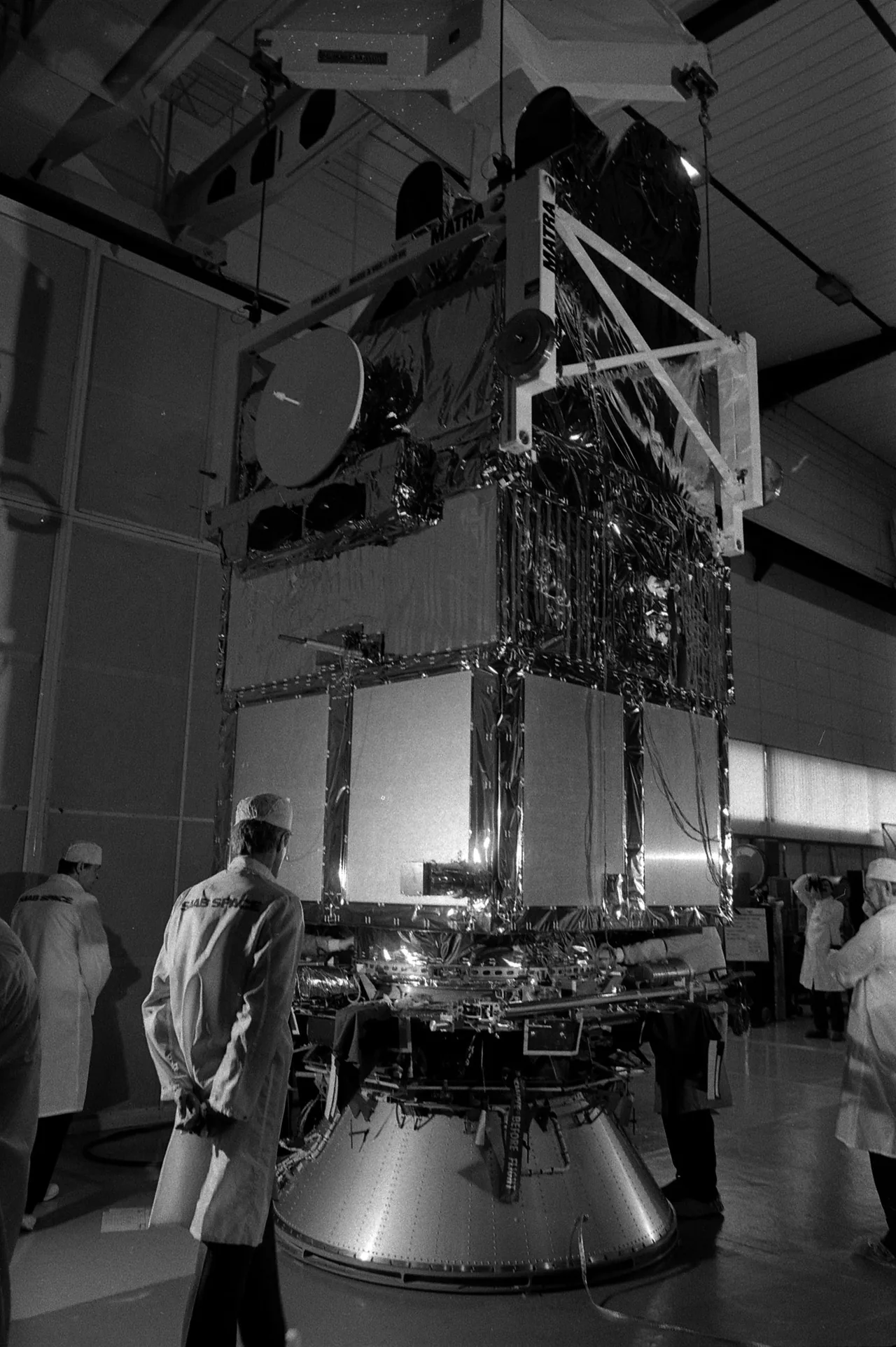 SPOT 1 stands above technicians on a handling frame in a black-and-white laboratory photograph