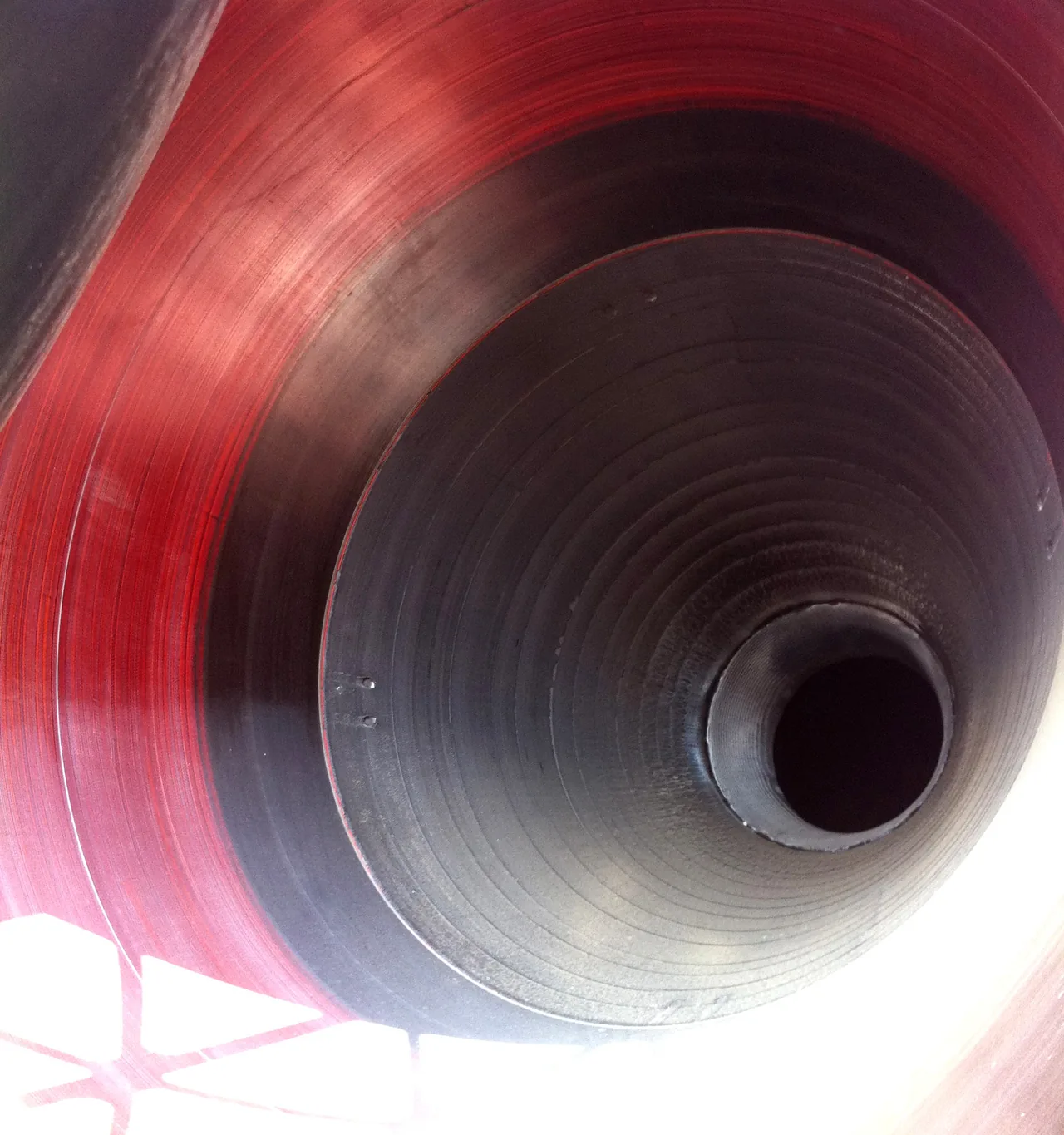 Close view into the dark concentric interior of an M-V second-stage rocket nozzle under red ambient light.