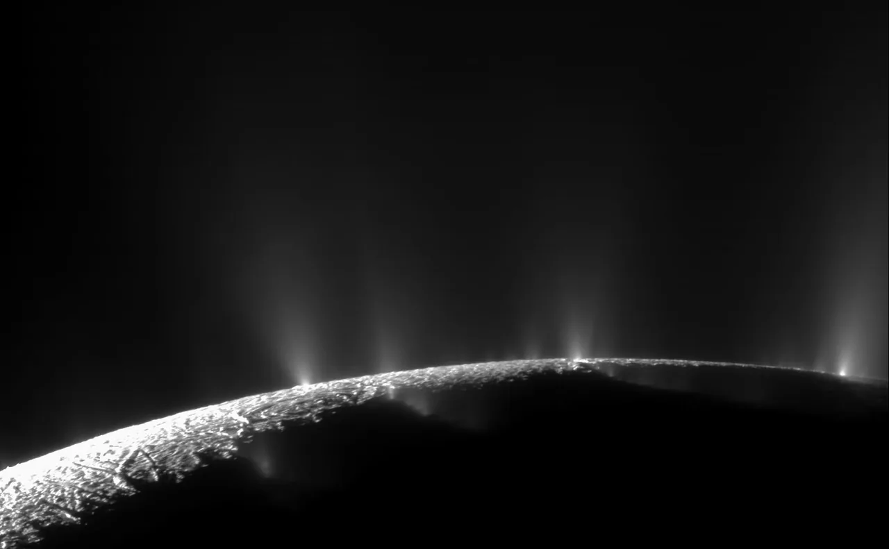 A bright curved limb of Enceladus lies below narrow and diffuse jets of light against dark space.