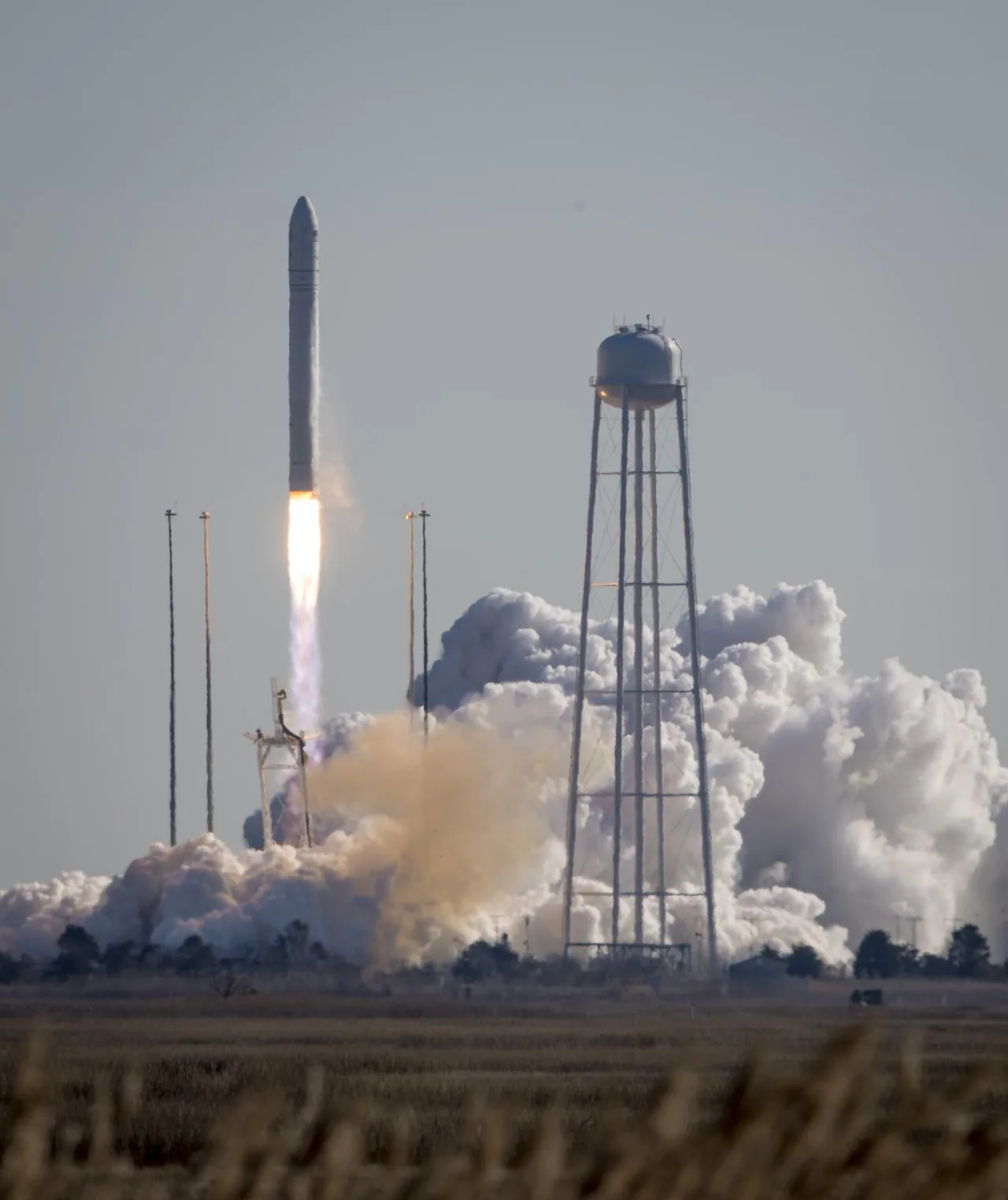 An Antares rocket climbs above its launch site with a bright exhaust plume