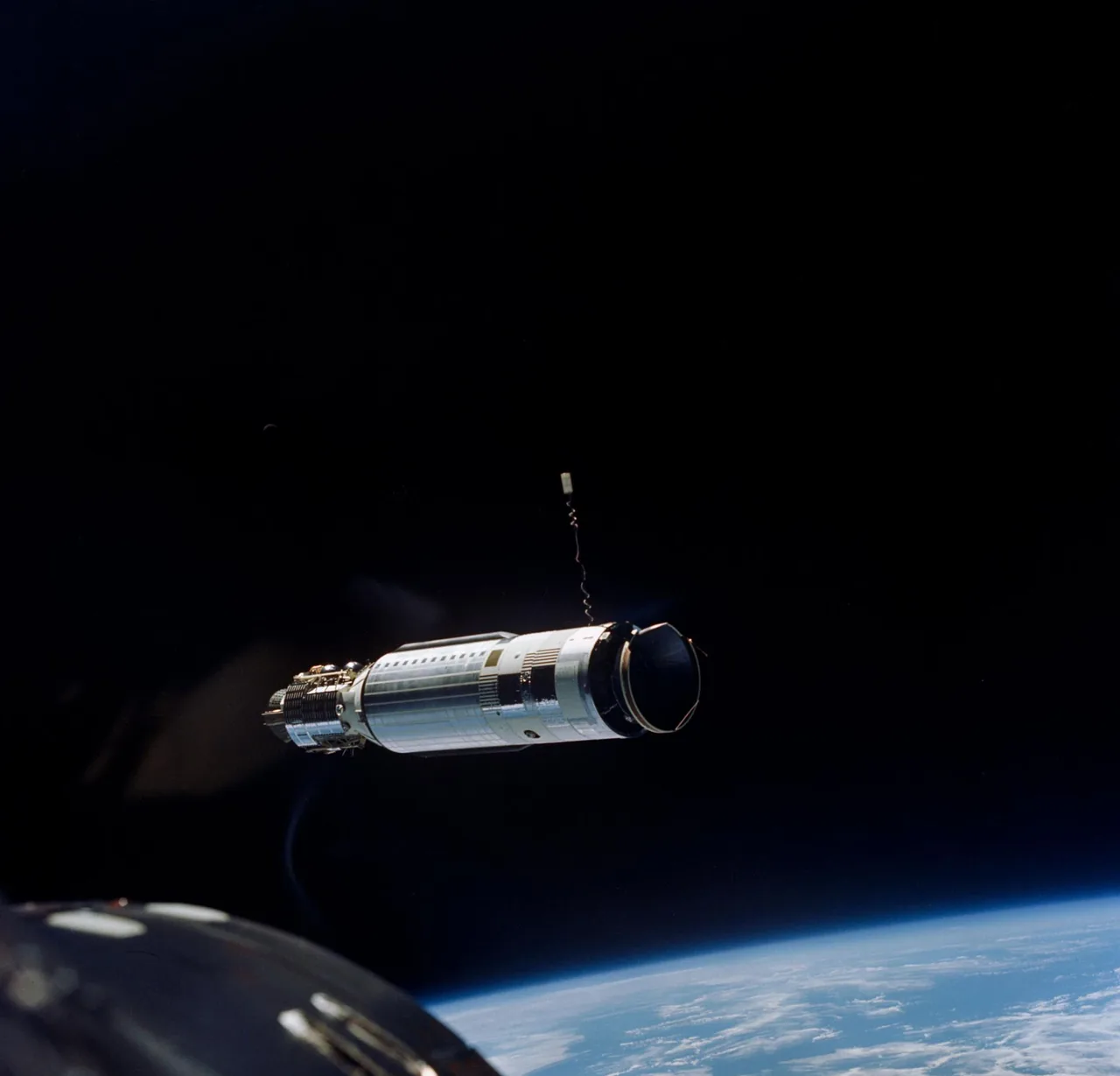 A cylindrical Agena target vehicle seen from Gemini 8 above Earth’s curved horizon