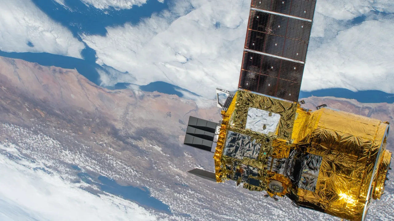A partial close view of HTV-X1 shows its foil-covered modules and a projecting solar array above the Pacific coast of Peru.