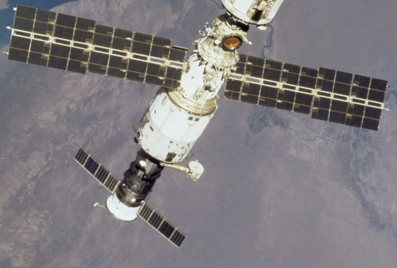 The Zvezda service module and a docked Progress cargo craft appear above Earth’s land and cloud patterns