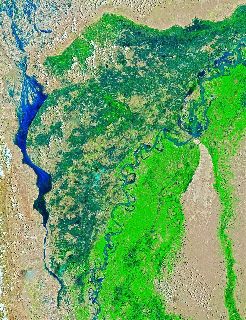 A winding river and narrow dark-blue lake cross green and tan terrain with scattered white clouds