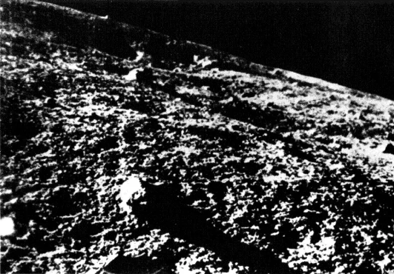 A grainy, high-contrast Luna 9 surface view shows nearby rough ground, a foreground rock, and a sloping displayed horizon.
