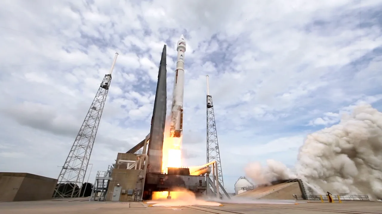 An Atlas V carrying MAVEN lifts off through a pale sky with a bright plume and smoke across the pad