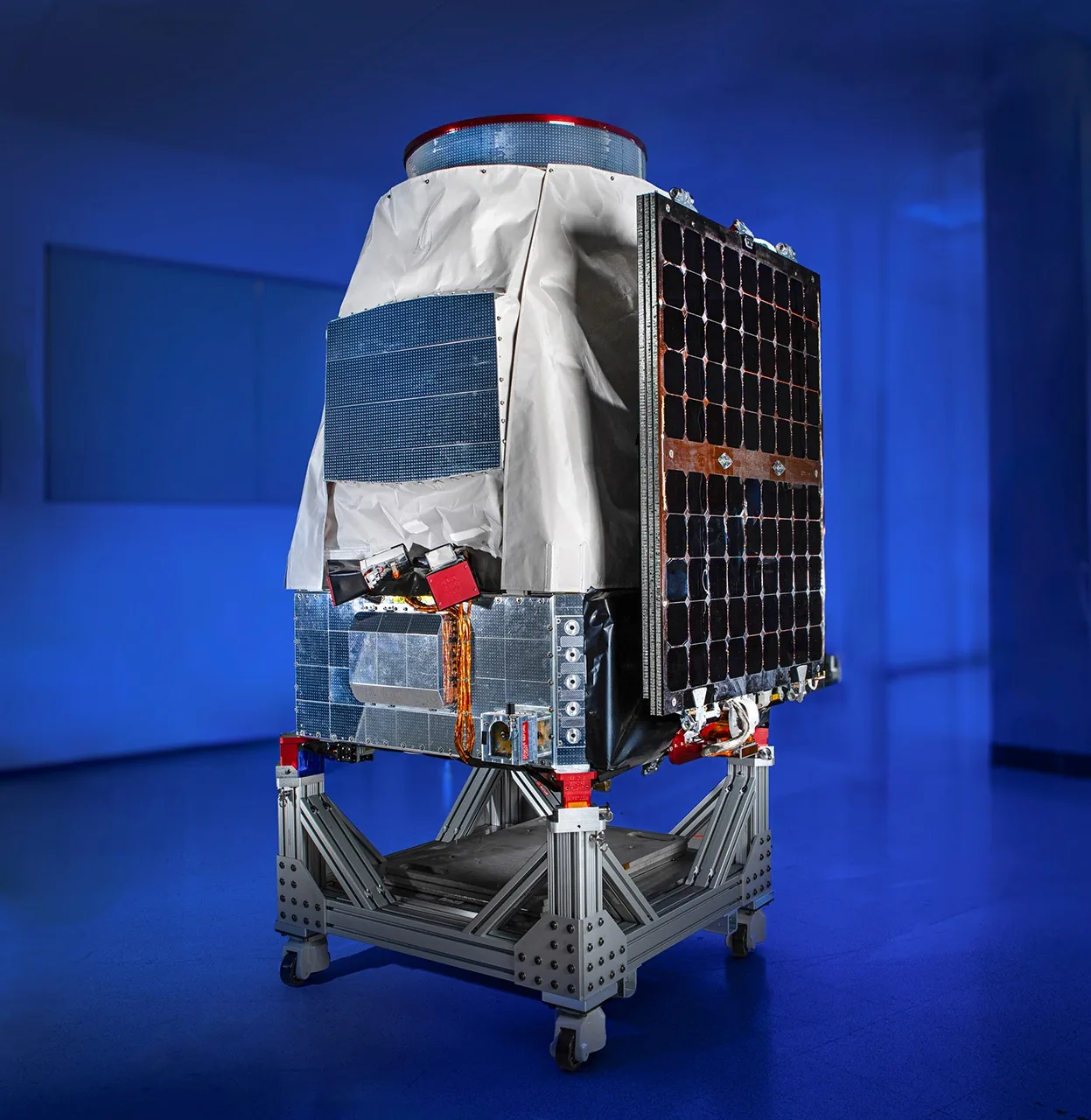 Pandora’s compact silver-covered spacecraft and dark solar cells stand against a blue studio background