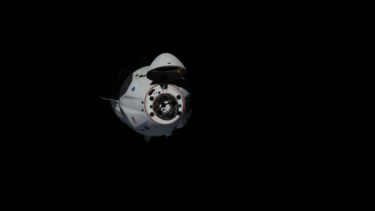 Crew Dragon approaches against black space with its nose cone open above the circular docking mechanism