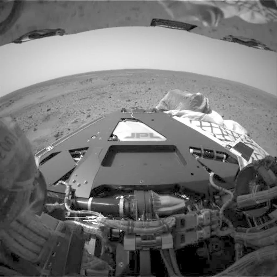 Spirit’s large wheels frame a wide-angle view of lander hardware and the Martian horizon.