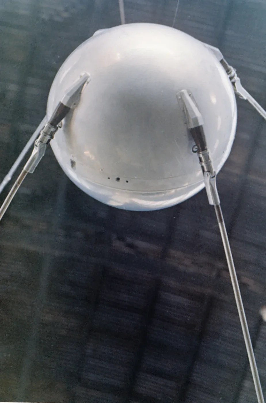 A polished spherical Sputnik model with long aerials, photographed on display