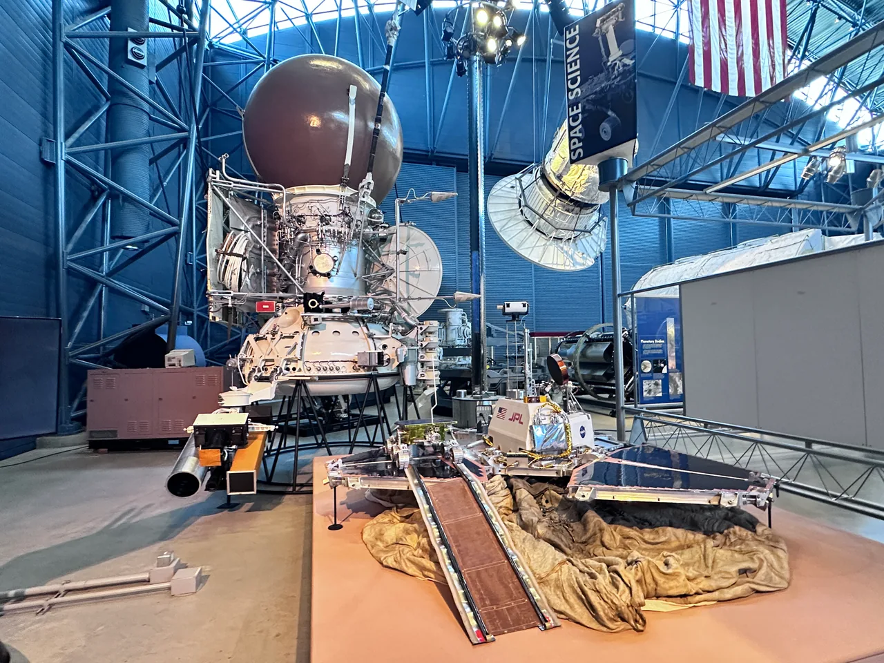 Vega bus and landing-apparatus engineering models behind other spacecraft exhibits at the Udvar-Hazy Center.