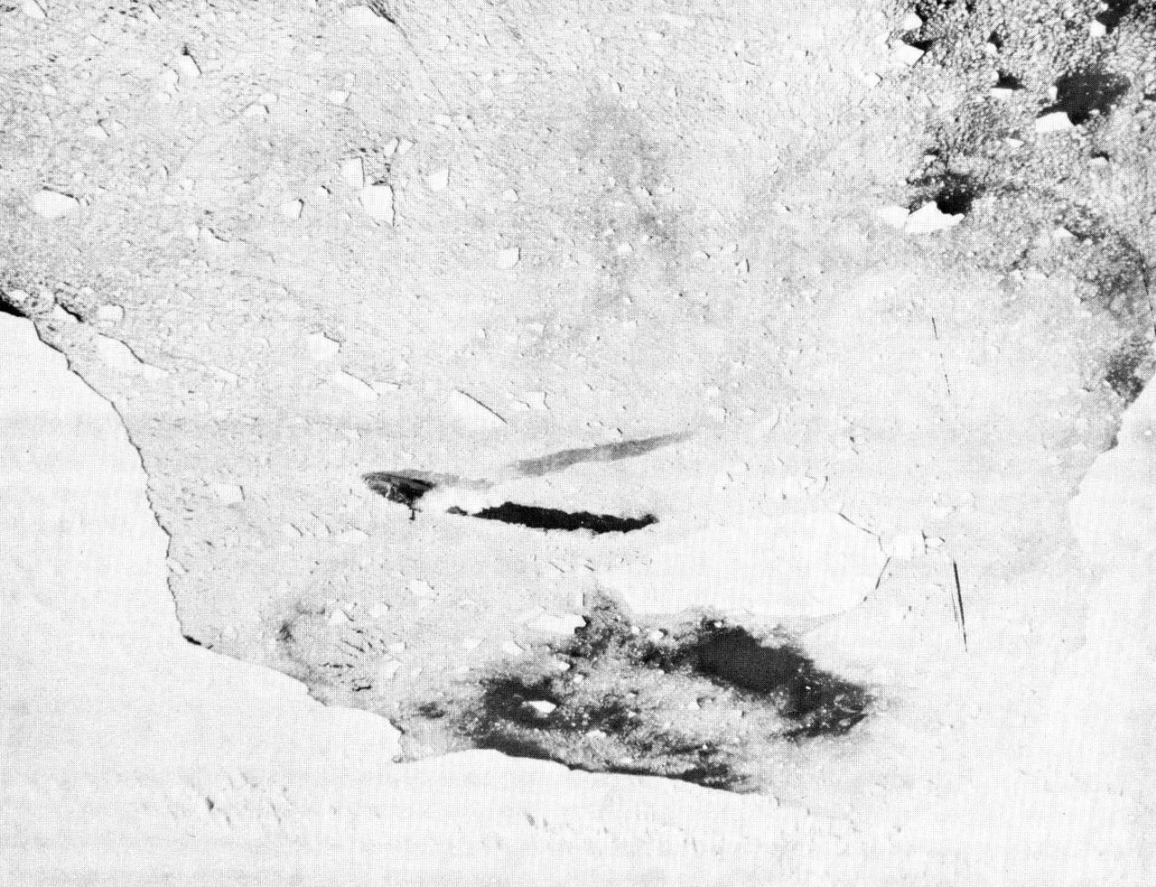 A small icebreaker amid bright sea ice, with dark openings and a cut channel behind it