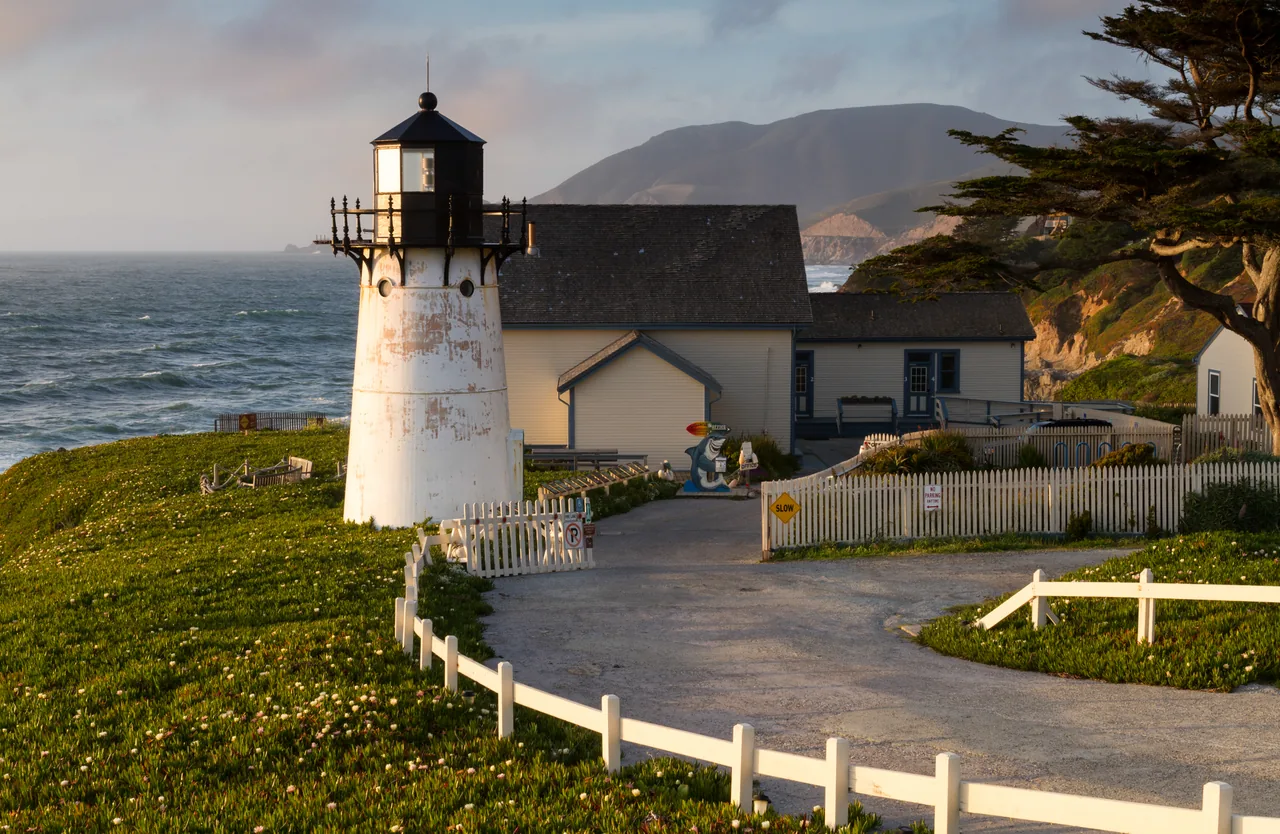 Ocean crests beside Point Montara Lighthouse and coastal cliffs in evening light