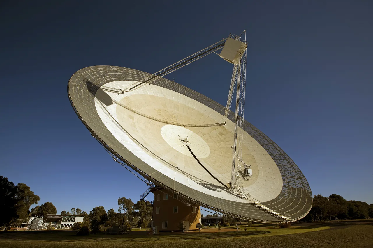 The large tilted Parkes radio telescope dish and its receiver support above a circular tower on a grassy site
