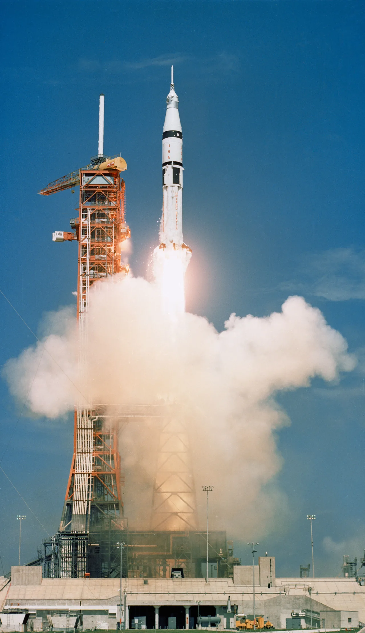 Apollo-Soyuz Test Project Apollo spacecraft lifting off on a Saturn IB beside the launch tower.