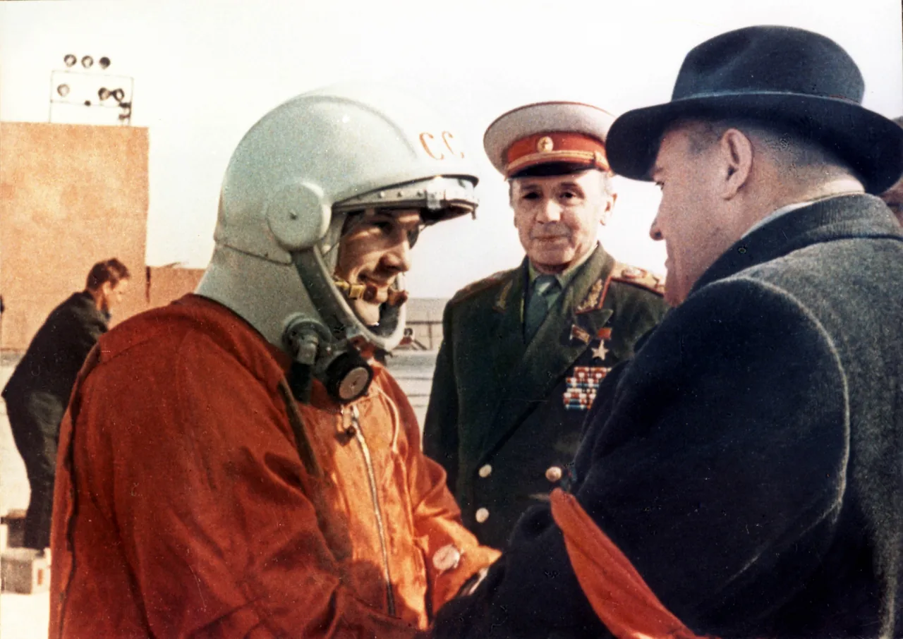 Yuri Gagarin in an orange pressure suit speaking with Sergei P. Korolev and a uniformed official before flight
