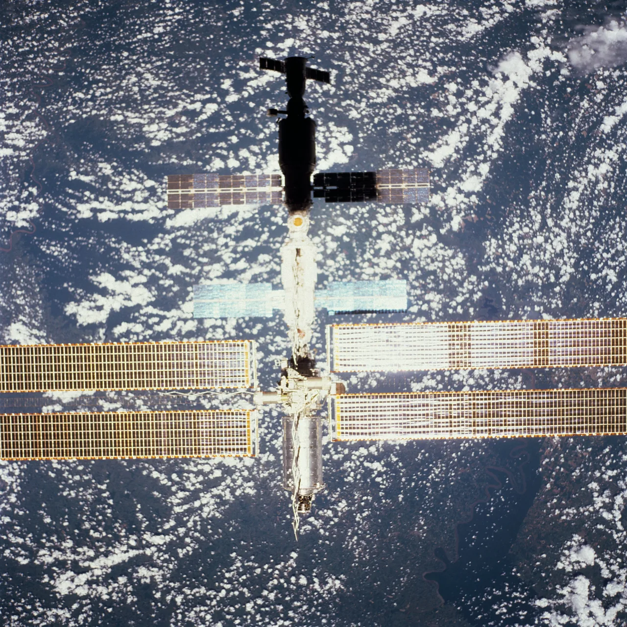 Exact Expedition 1 International Space Station configuration with the newly attached Destiny laboratory and solar arrays above cloud-covered Earth