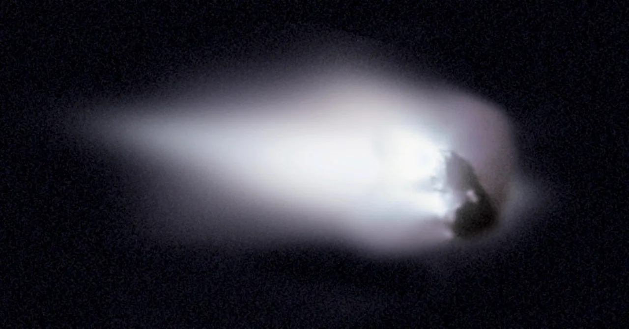 An enhanced Giotto image shows Halley’s dark irregular nucleus on the right, with a broad bright plume spreading left into surrounding black space.