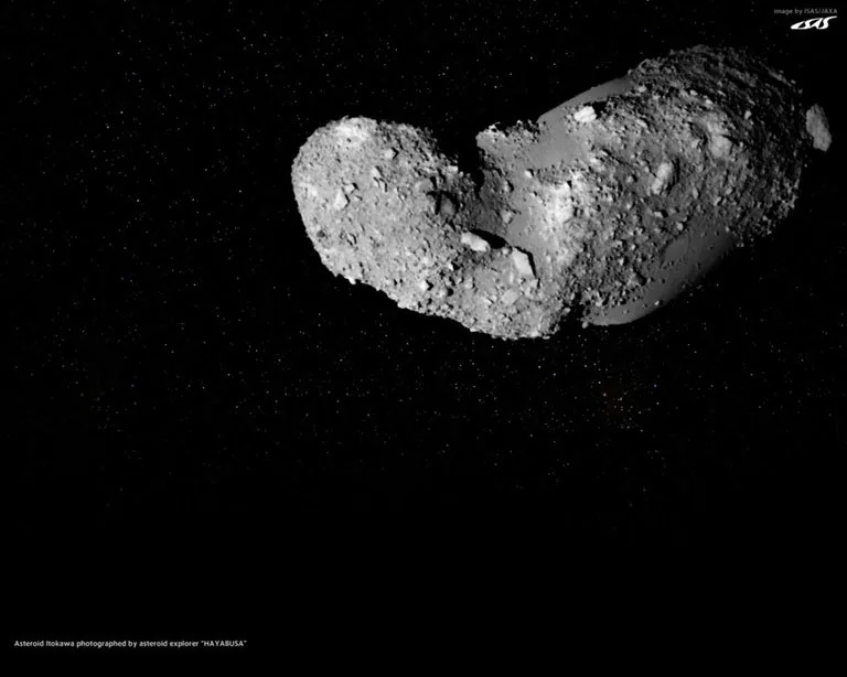 Hayabusa view of two-lobed Itokawa, with rough boulder-covered regions and a smoother area between them; the original image retains JAXA labels.