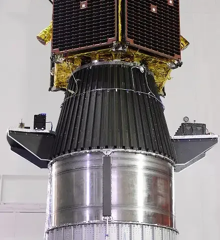 Solar-panel-covered spacecraft hardware above a black conical adapter with smaller equipment on side platforms and a metallic cylinder below