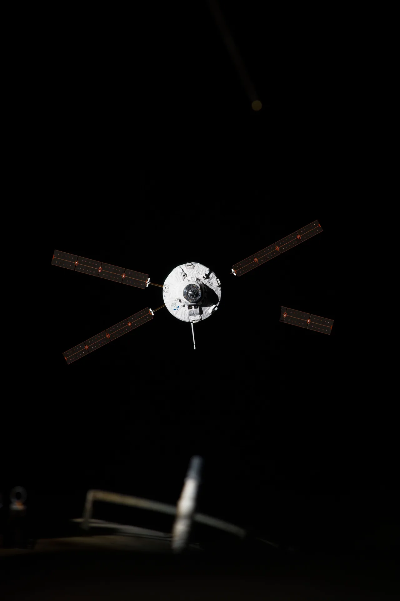 The circular docking end of ATV-5 faces the camera, with four solar-array wings extended against black space