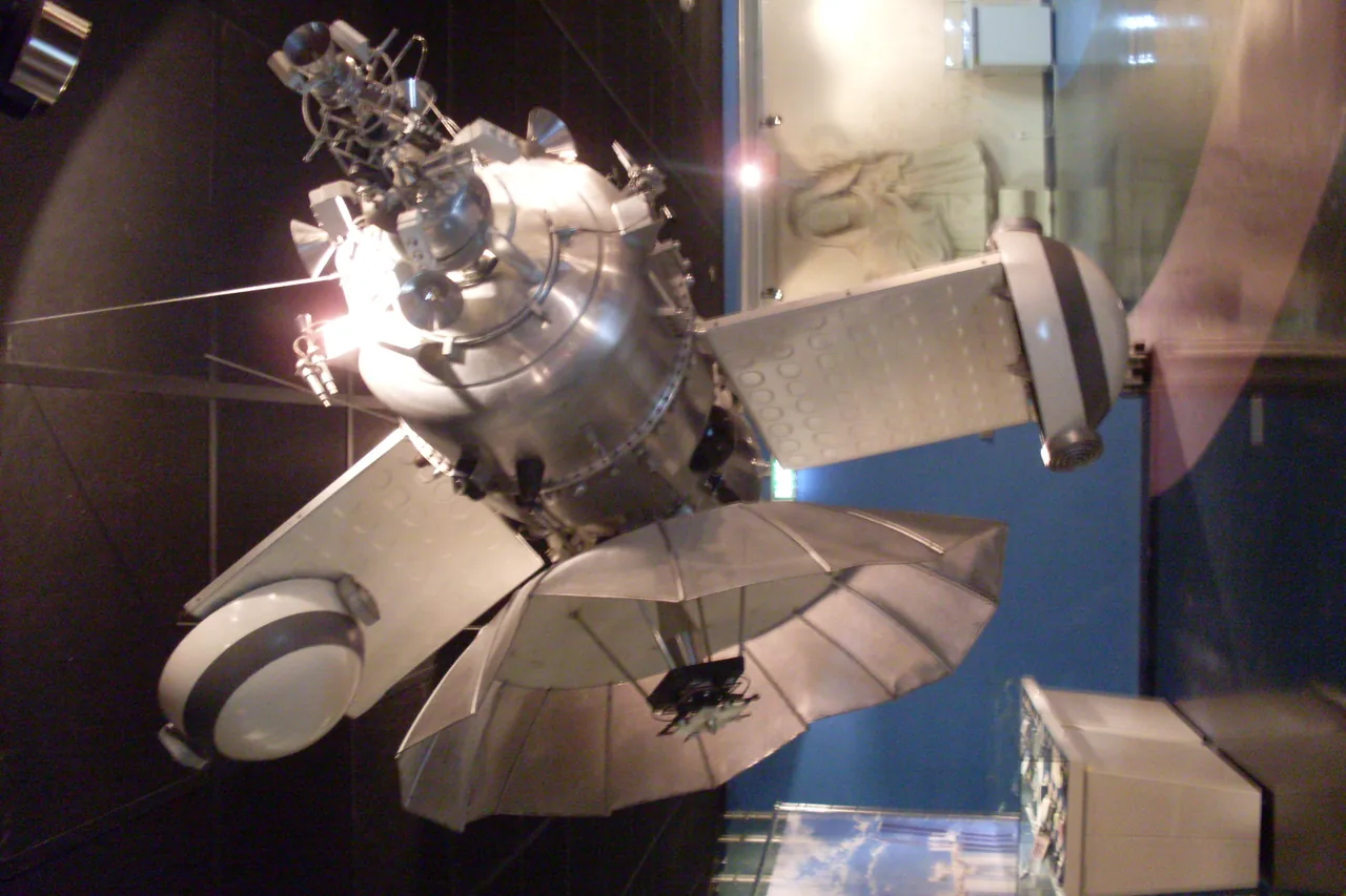 A metallic Mars 1 scale model with solar panels and antennas suspended in a museum.