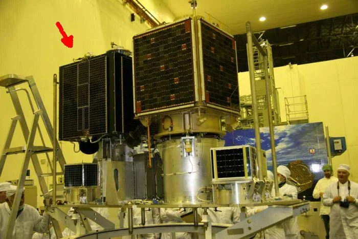Several box-shaped satellites stand in a cleanroom, with an arrow identifying EgyptSat-1 at the upper left
