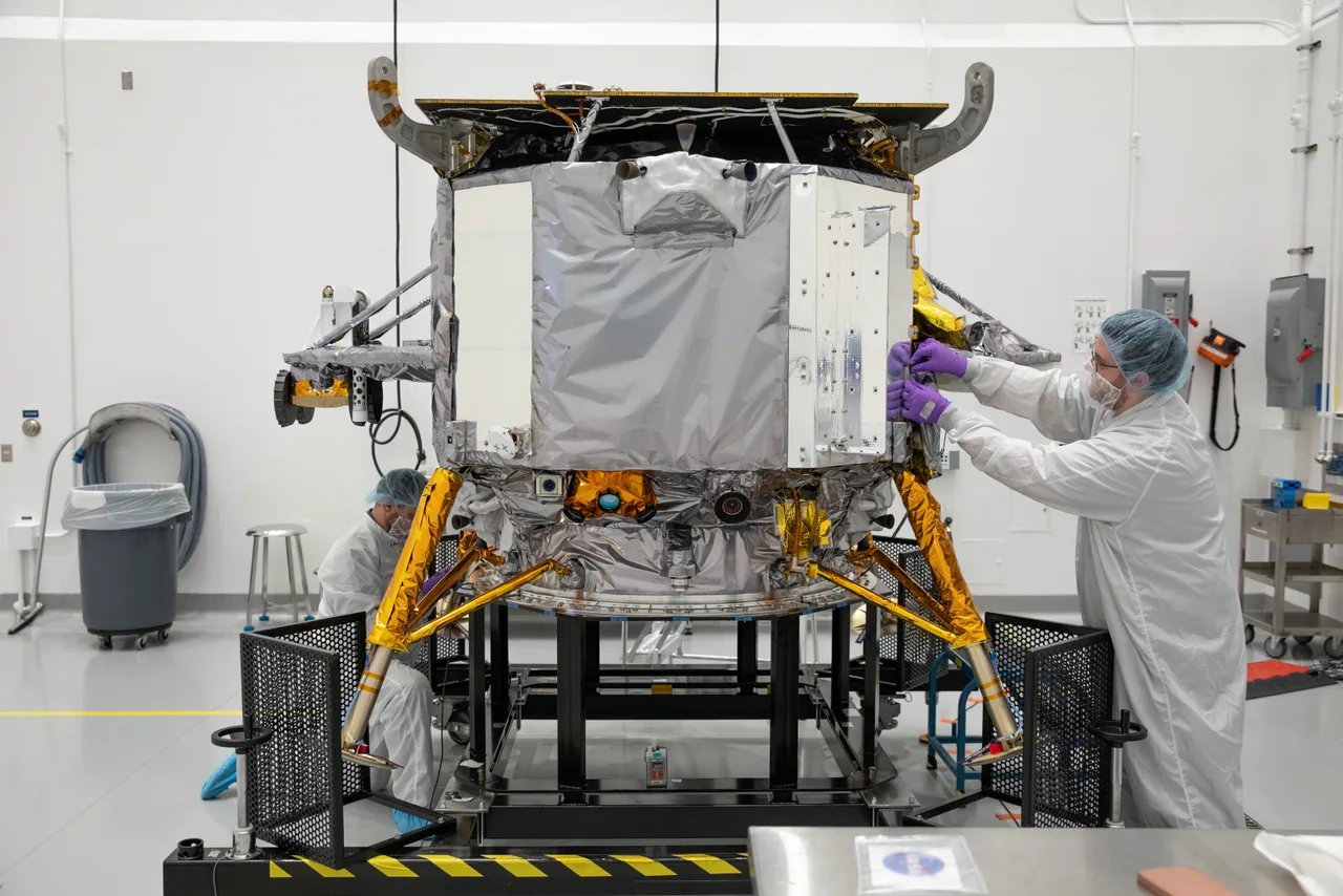 Cleanroom technicians work beside Peregrine’s foil-covered body and gold-colored landing legs