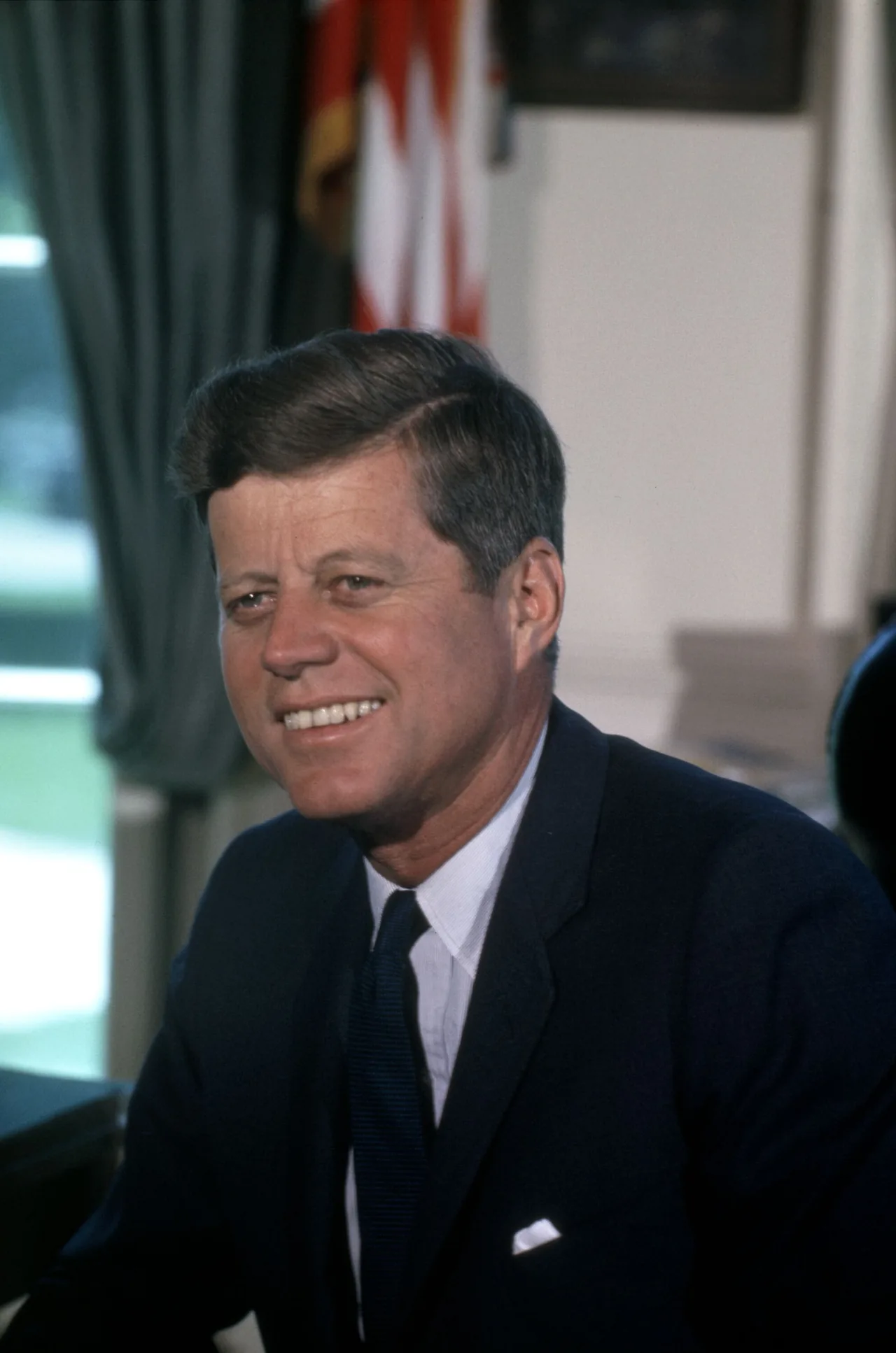 John F. Kennedy sits at a desk in an official White House portrait