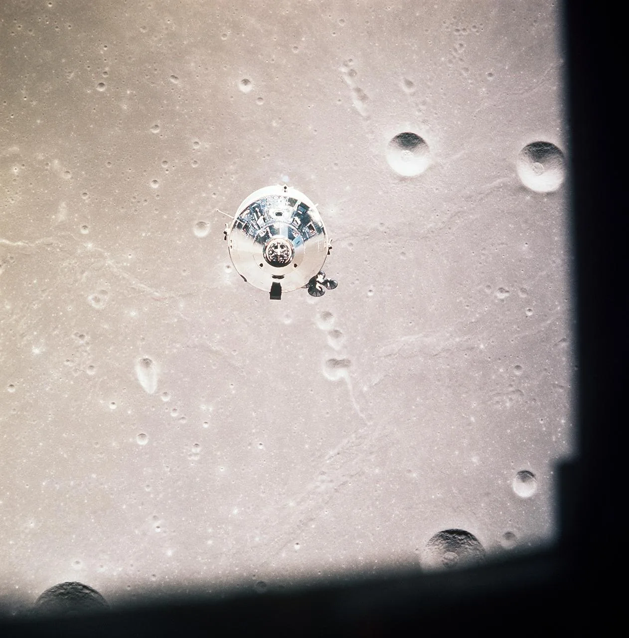 The Apollo command and service module appears above a cratered lunar surface