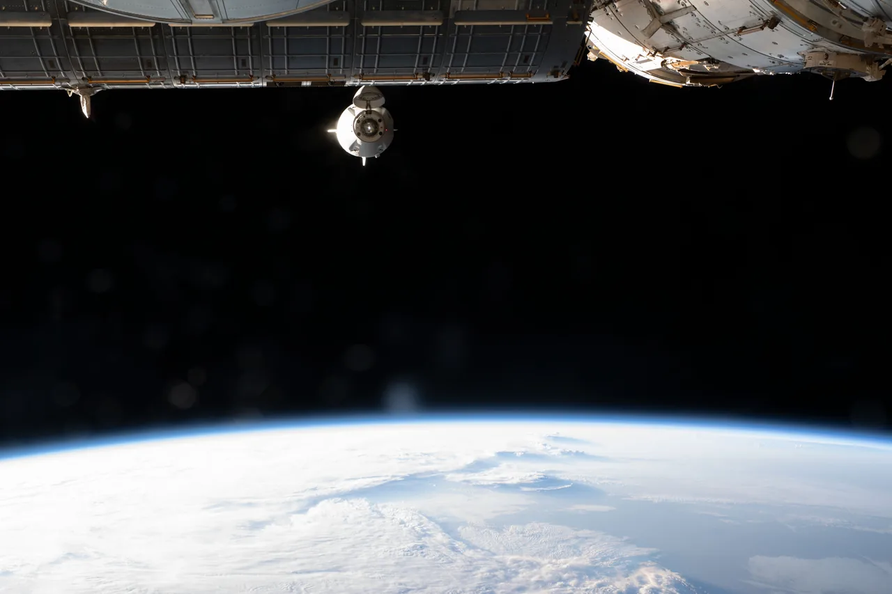Crew Dragon Endeavour approaches beneath a station structure, with the curved blue Earth below.