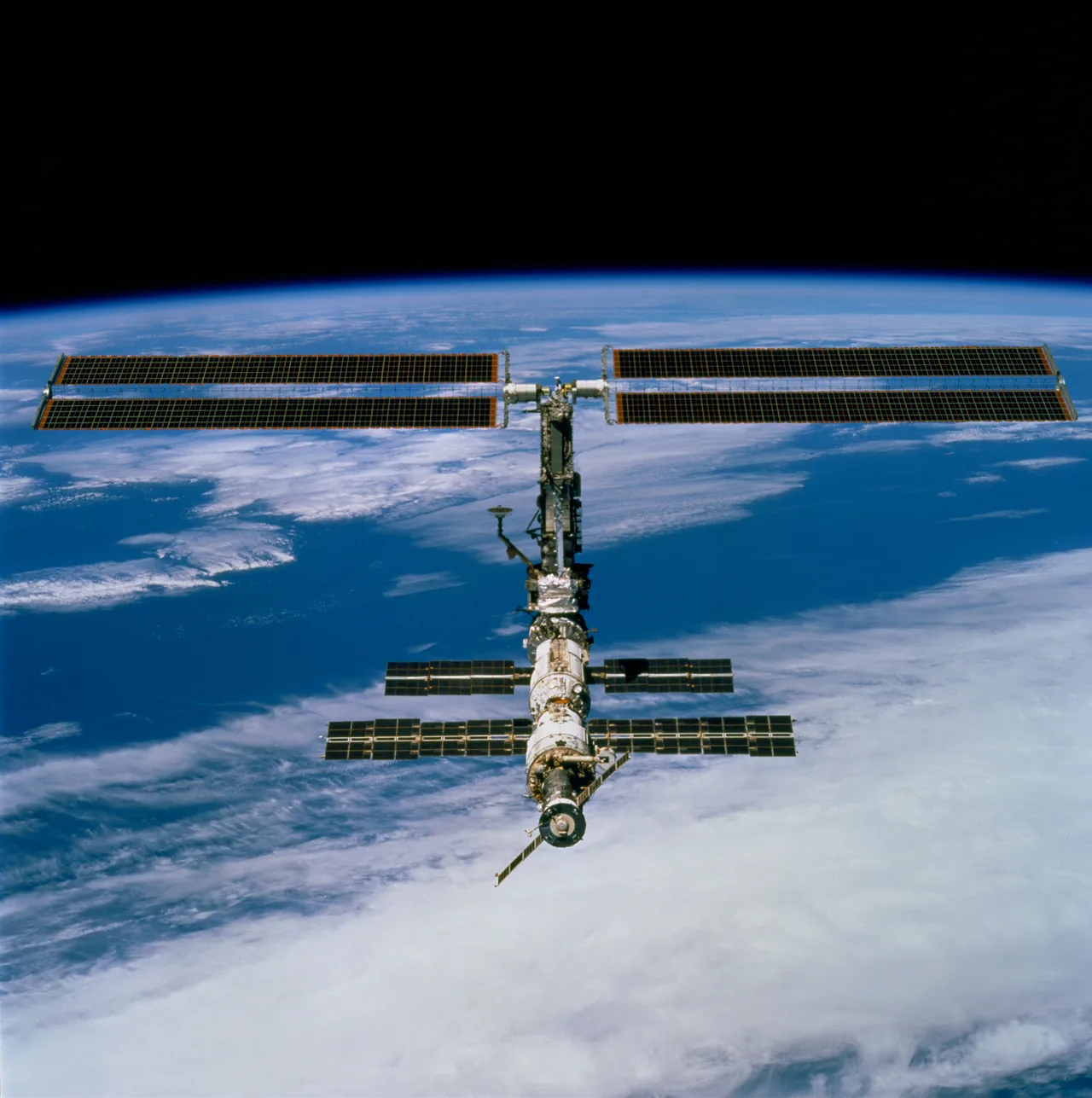 The exact Expedition 1 International Space Station configuration above Earth after STS-97, with the P6 solar arrays, Russian modules, and docked Soyuz visibly resolved.