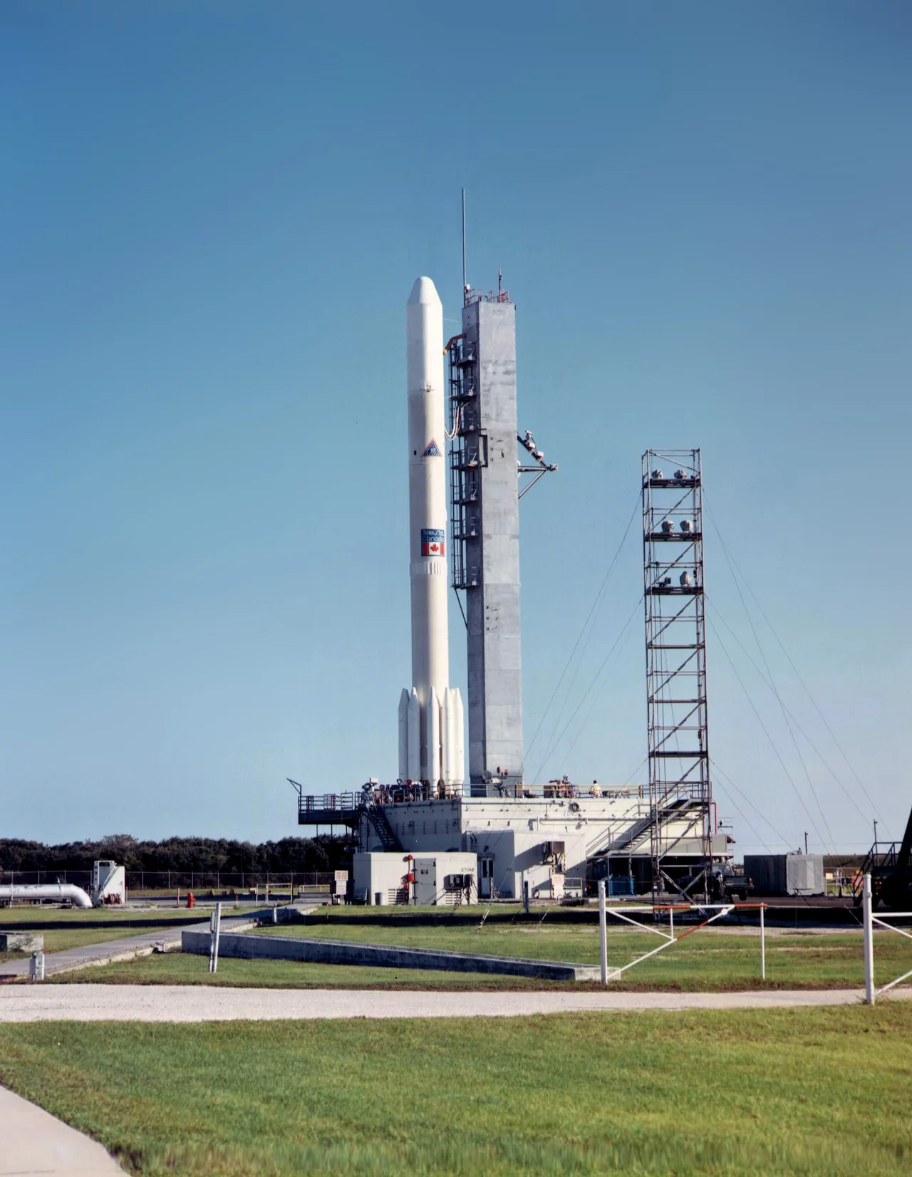 Delta 1914 carrying Anik A1 stands beside its service tower before launch
