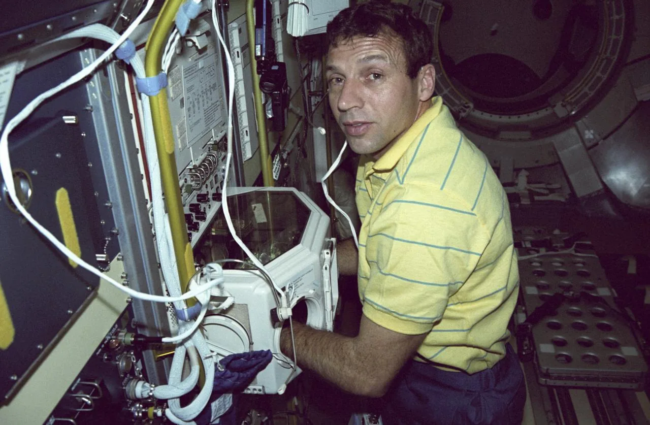 David Carl Hilmers works at a glovebox inside an orbiting laboratory