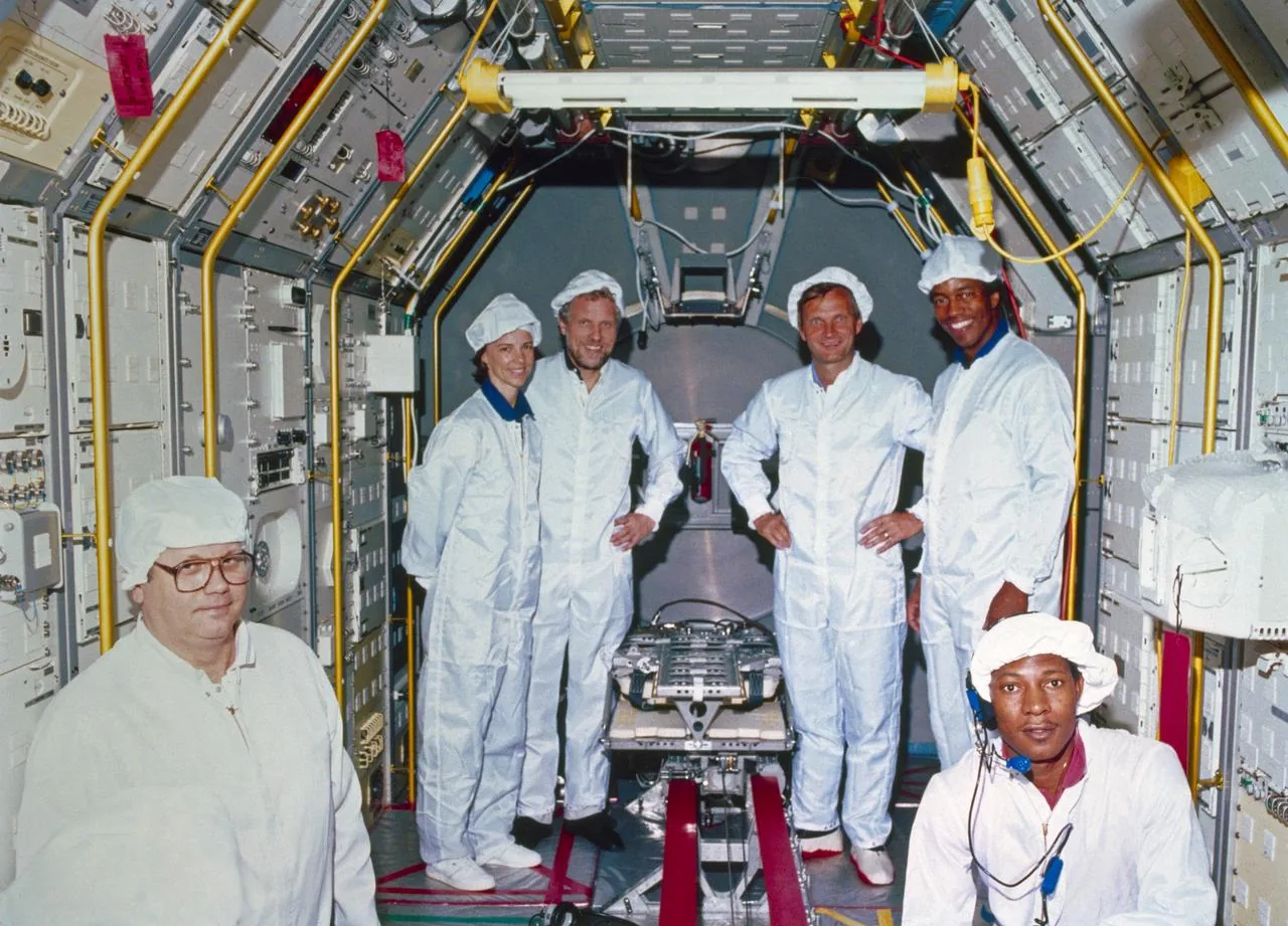 Crew members and technicians surround a vestibular sled inside a Spacelab module during ground preparation
