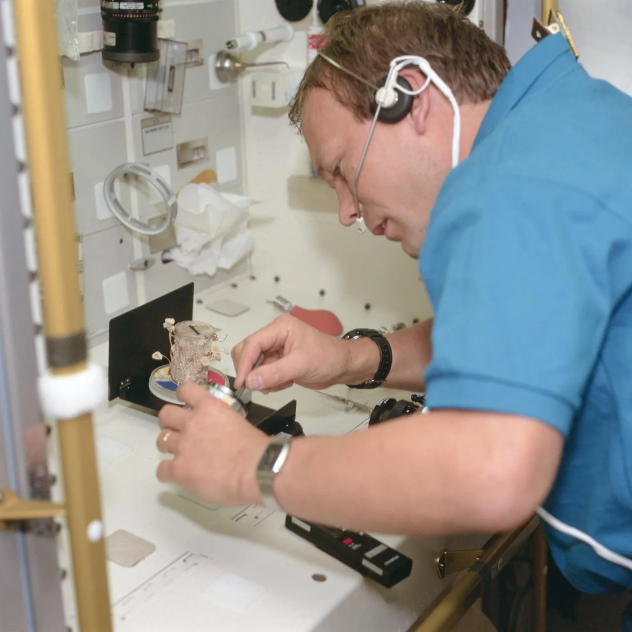 Hans Schlegel handles a small experiment container beside Spacelab equipment